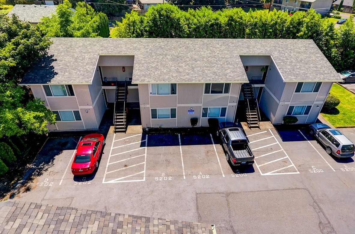 An aerial view of a apartment building with cars parked in front of it.
