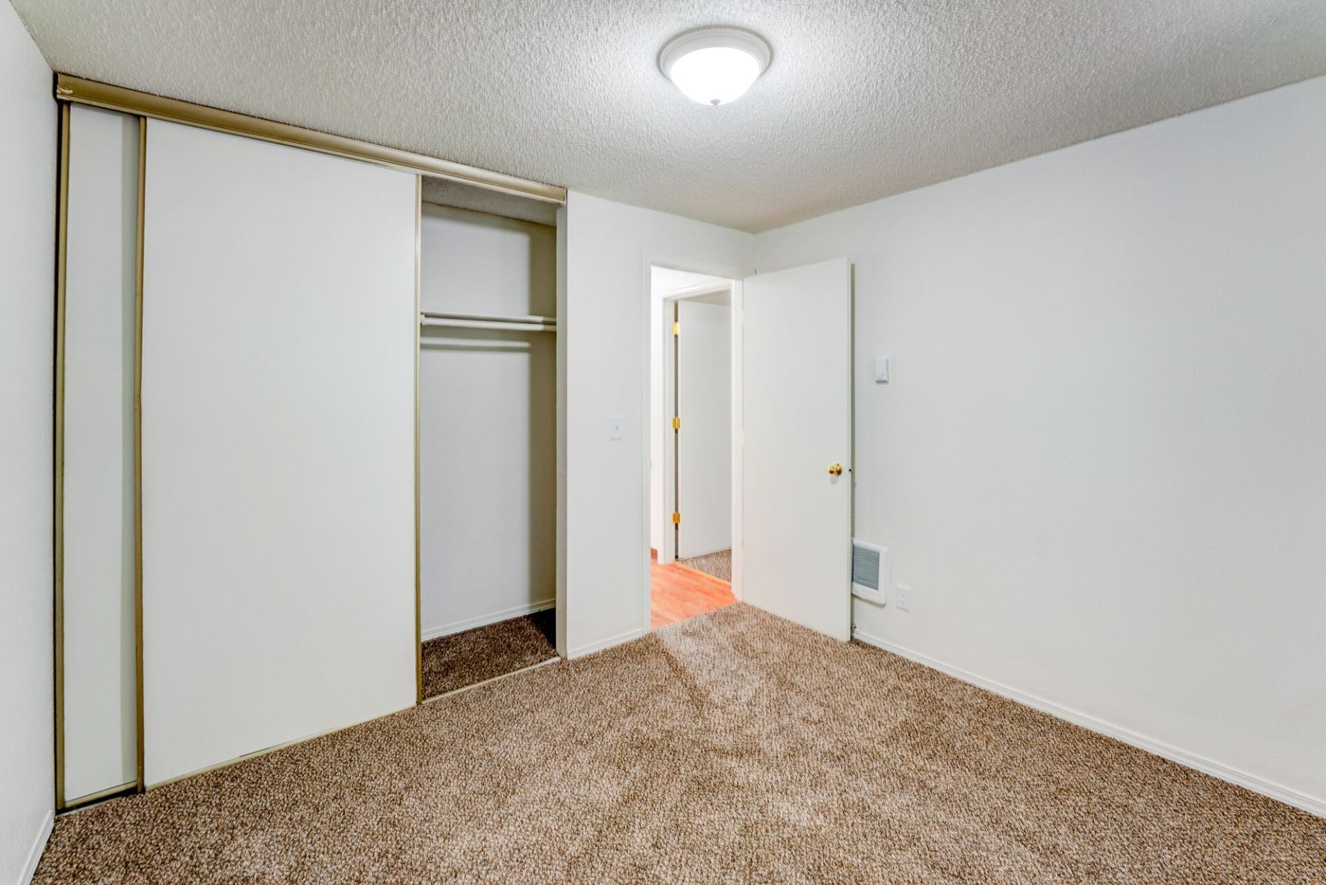 An empty bedroom with sliding glass doors and a closet.