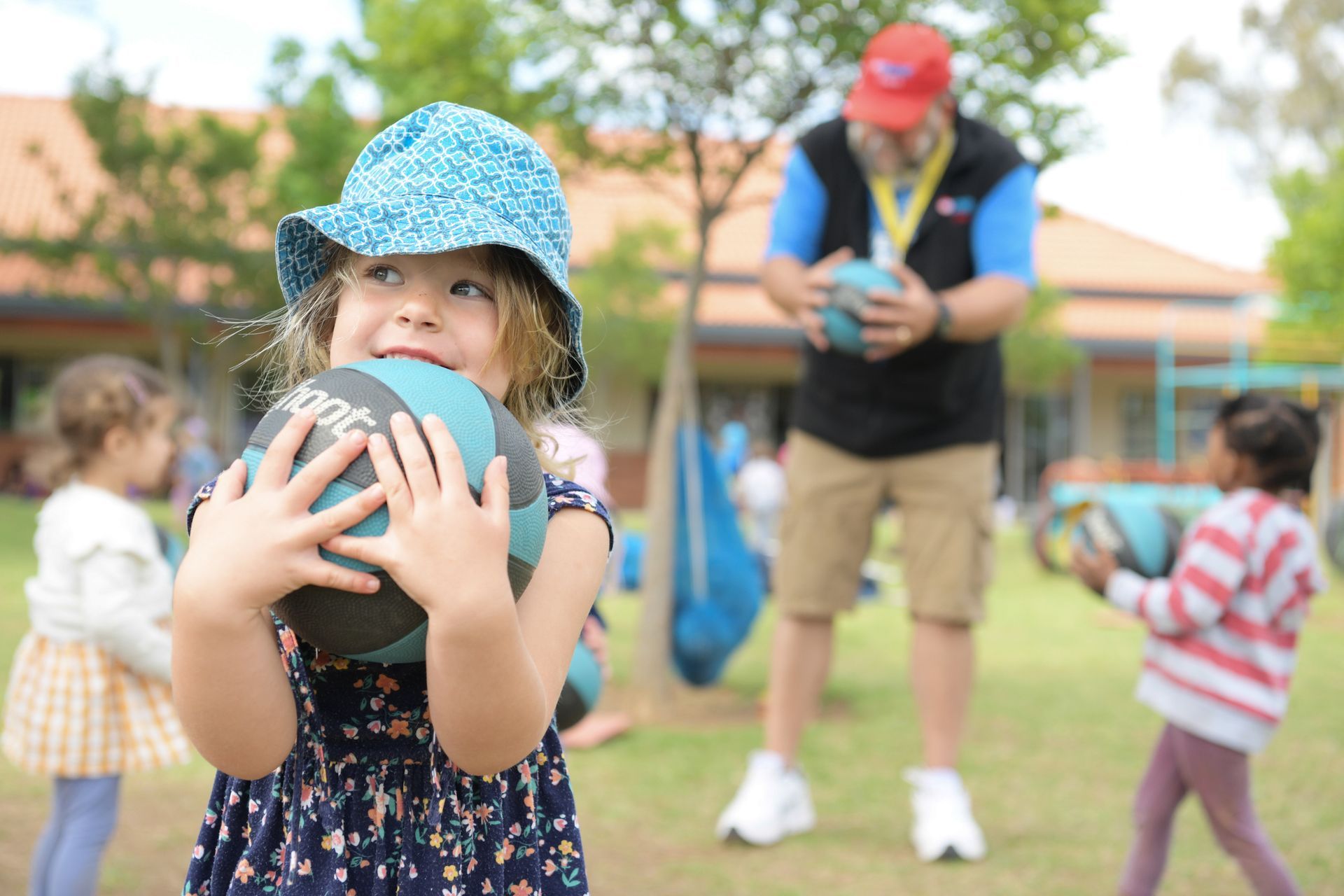 a little girl is holding a ball in her hands .