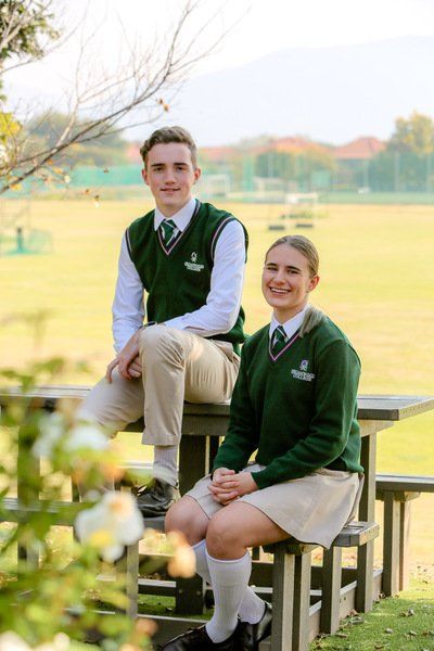 a boy and a girl in school uniforms are sitting at a picnic table .