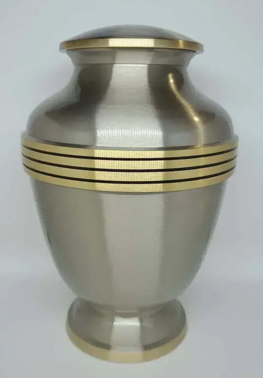 A silver urn with a gold stripe on the side is sitting on a white table.