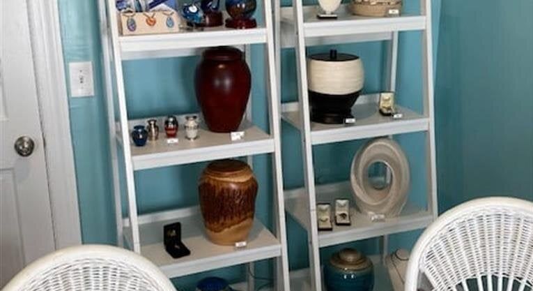 A room with two chairs and two shelves with vases on them.