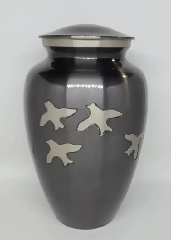 A black vase with birds on it is sitting on a table.
