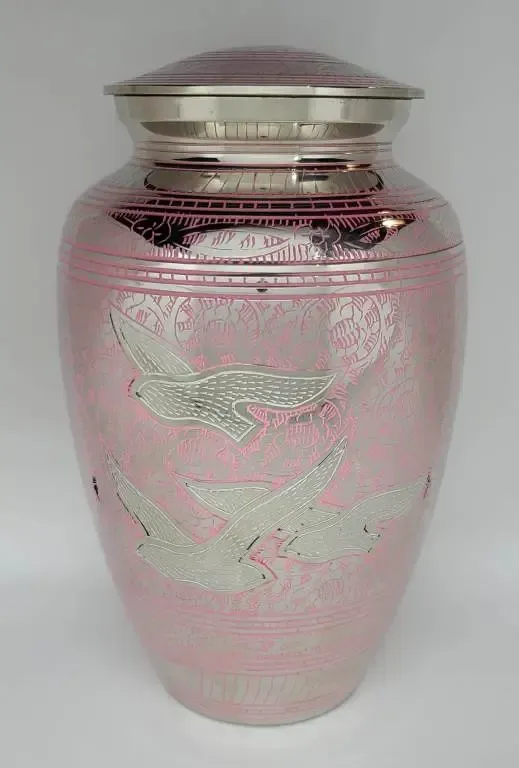 A pink urn with birds on it is sitting on a table.