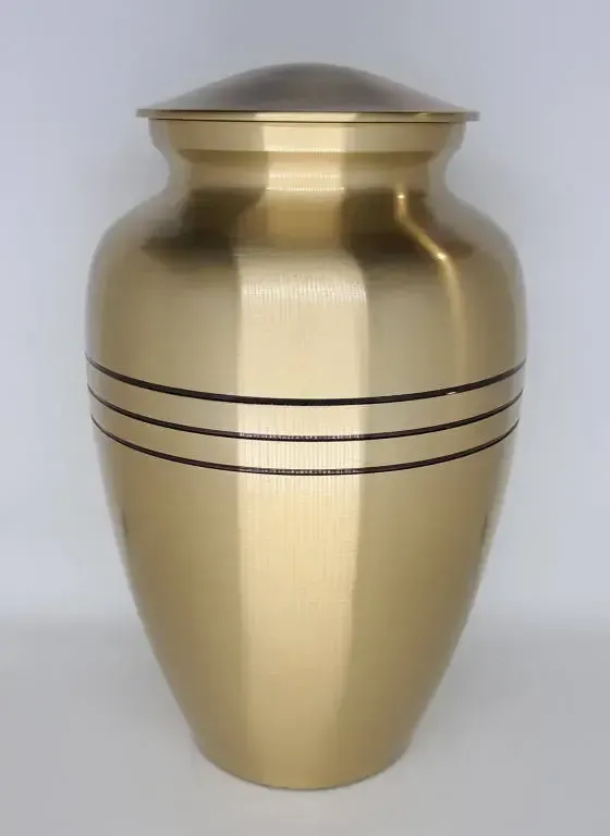 A gold urn with three black stripes on it is sitting on a table.