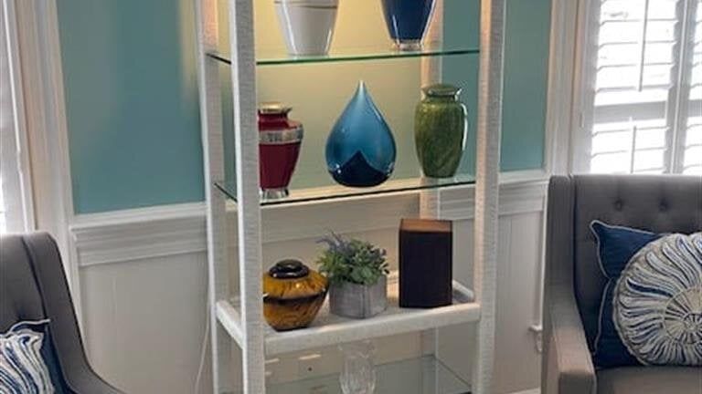 A living room with a shelf filled with vases and urns.
