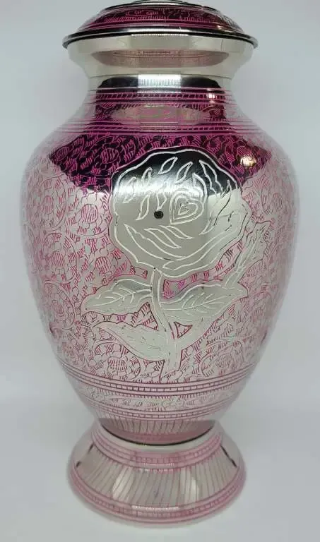 A pink urn with a silver design on it is sitting on a white surface.