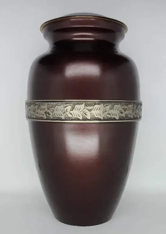 A brown vase with a silver ribbon on it is sitting on a white surface.