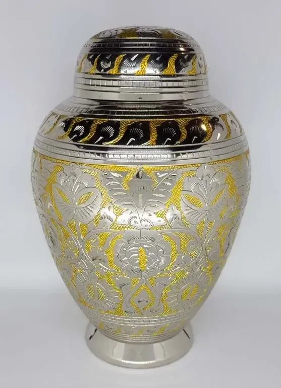 A silver and gold urn with a lid is sitting on a table.