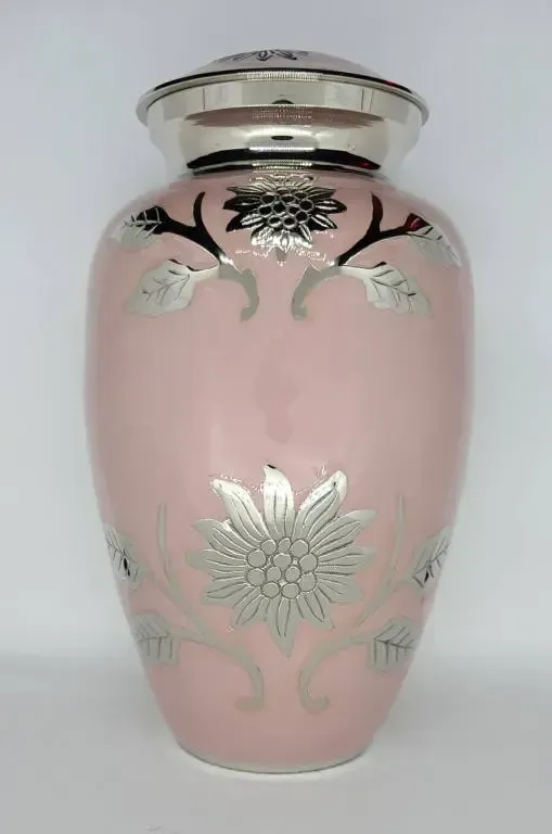 A pink vase with a silver flower on it is sitting on a table.