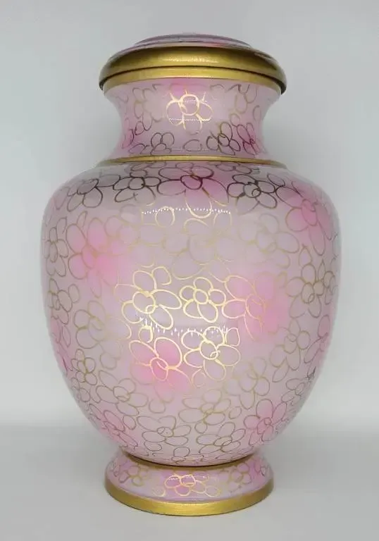 A pink vase with gold flowers on it is sitting on a white table.
