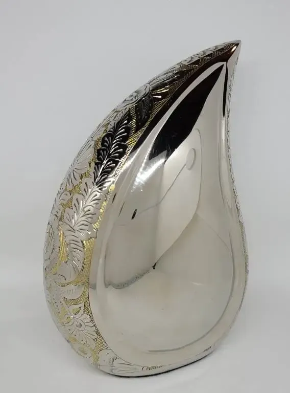 A silver vase in the shape of a teardrop is sitting on a white surface.