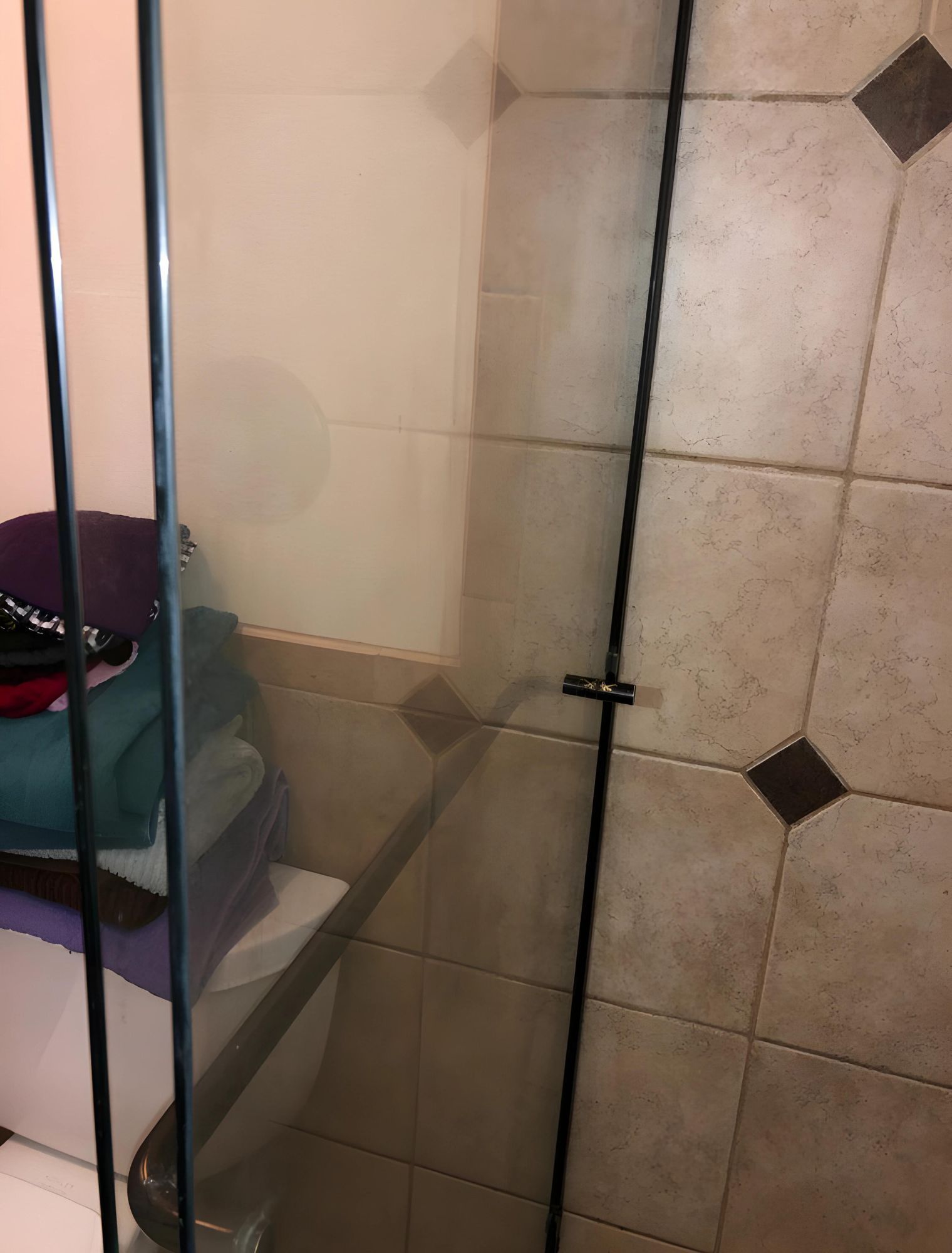 A bathroom with a glass shower door and a stack of towels on the floor.