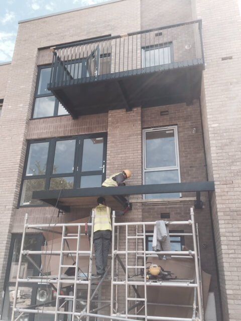 Installers attaching balconies to a flat block