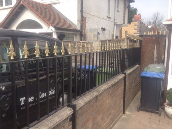 Black fencing with gold points separating two houses