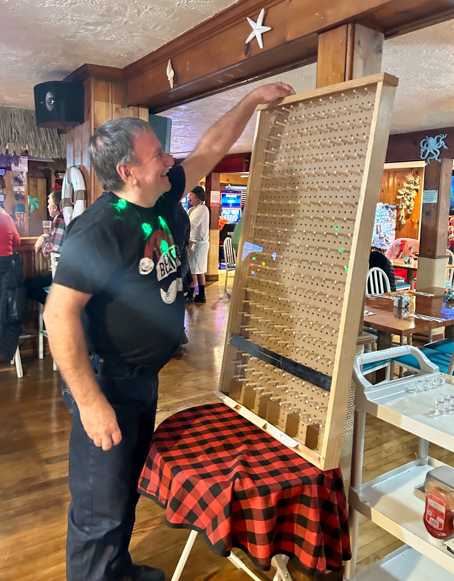 A man in a black shirt is standing next to a table with a checkered tablecloth.
