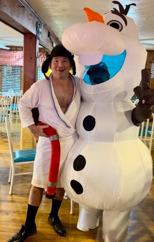 A man in a bathrobe is standing next to a snowman costume.
