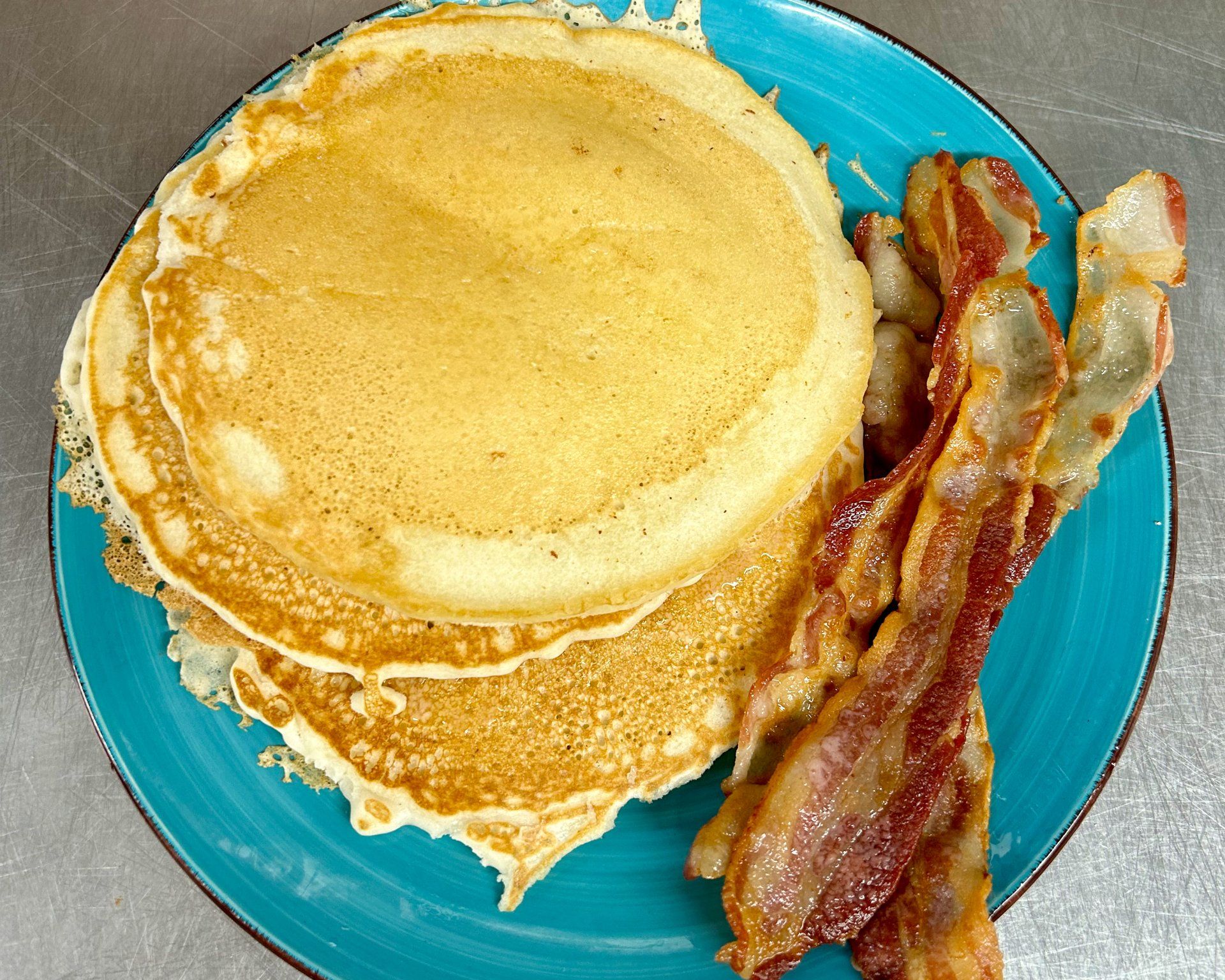 A blue plate with pancakes and bacon on it