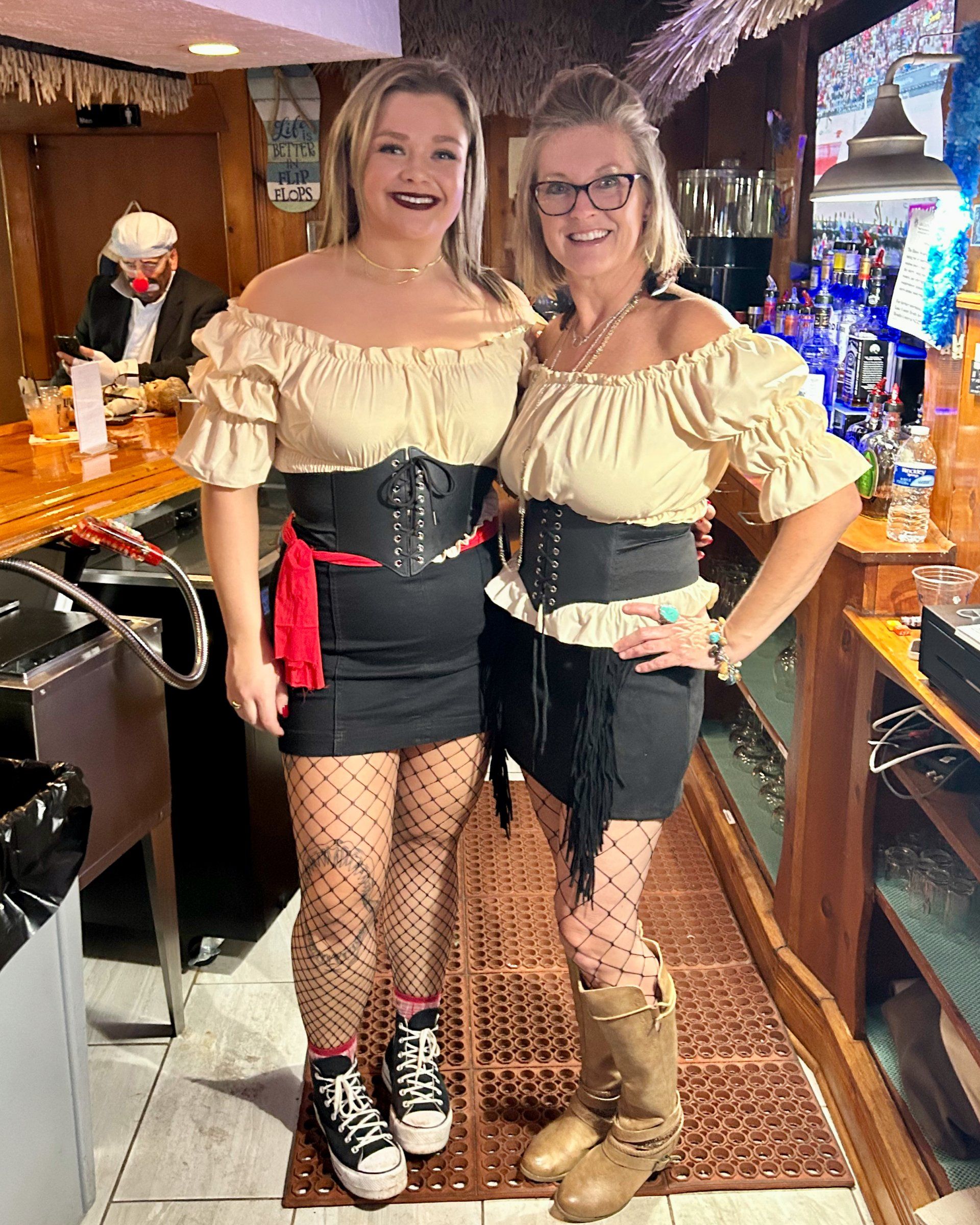 Two women in pirate costumes are standing next to each other in a bar.