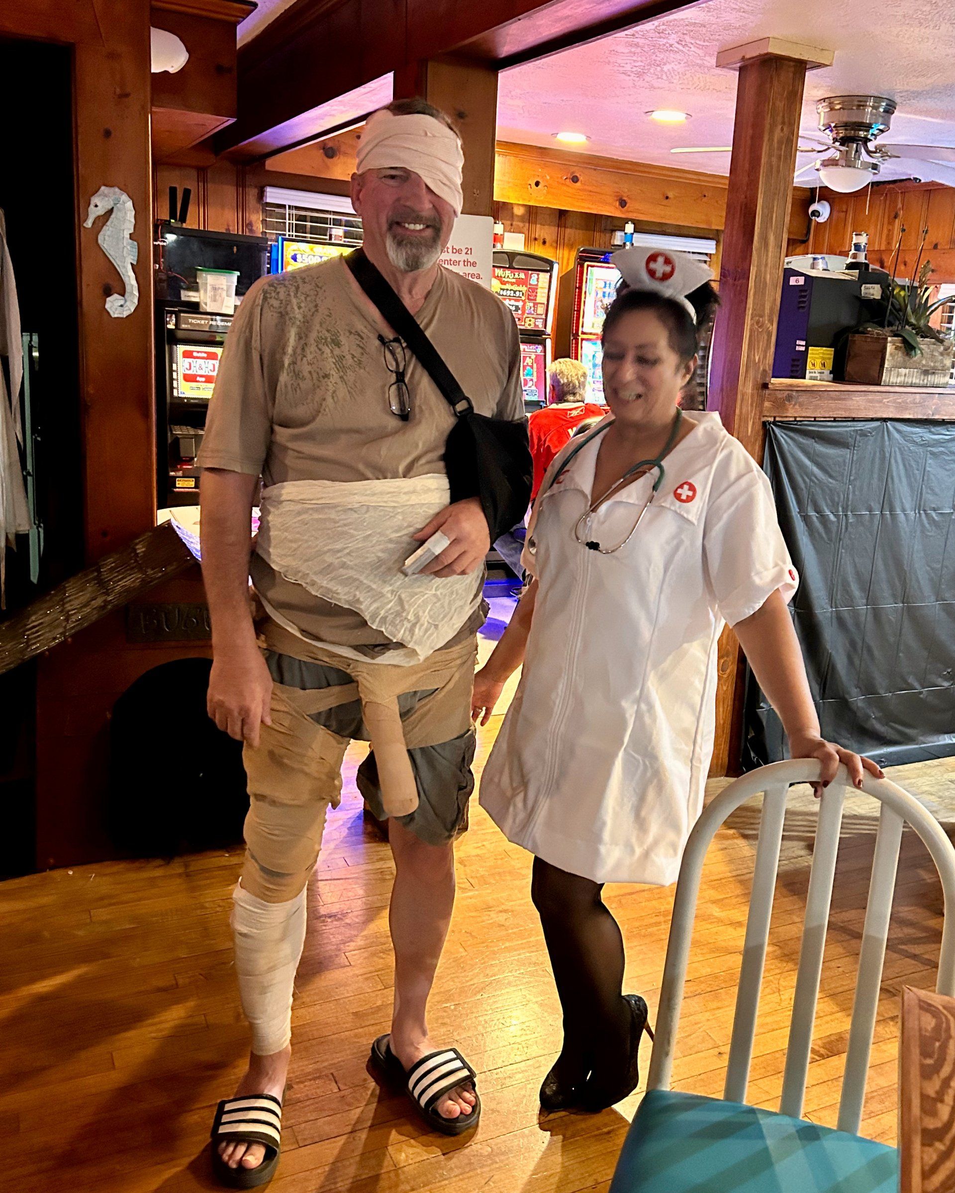 A man with a cast on his arm is standing next to a woman dressed as a nurse.