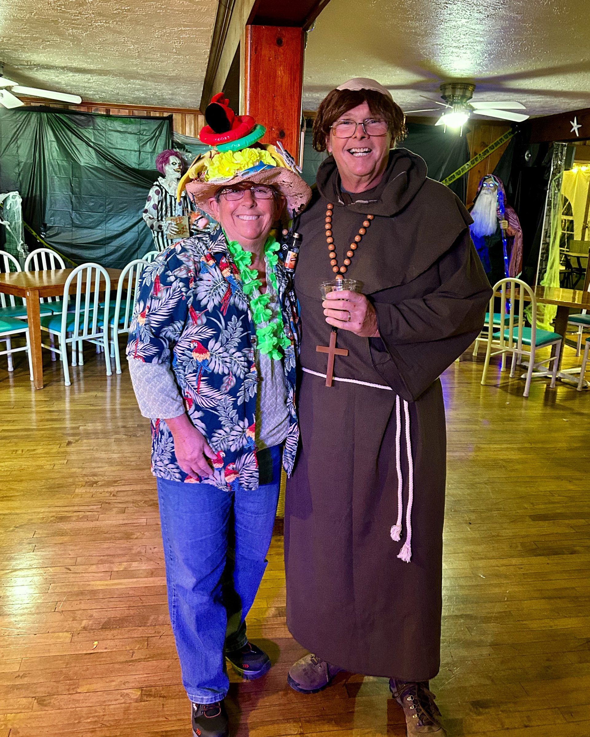 A man in a monk costume stands next to a woman in a colorful hat.