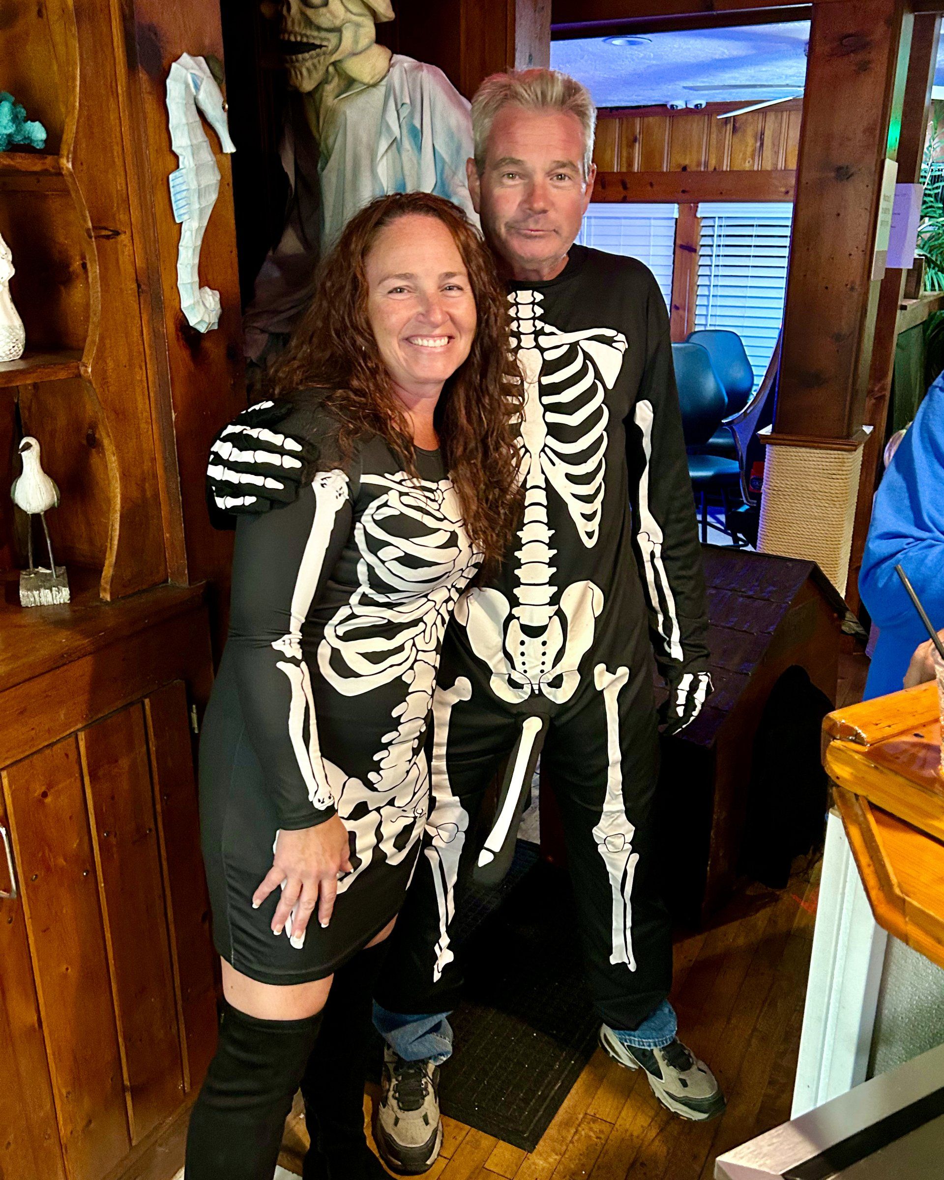 A man and a woman are posing for a picture in skeleton costumes.