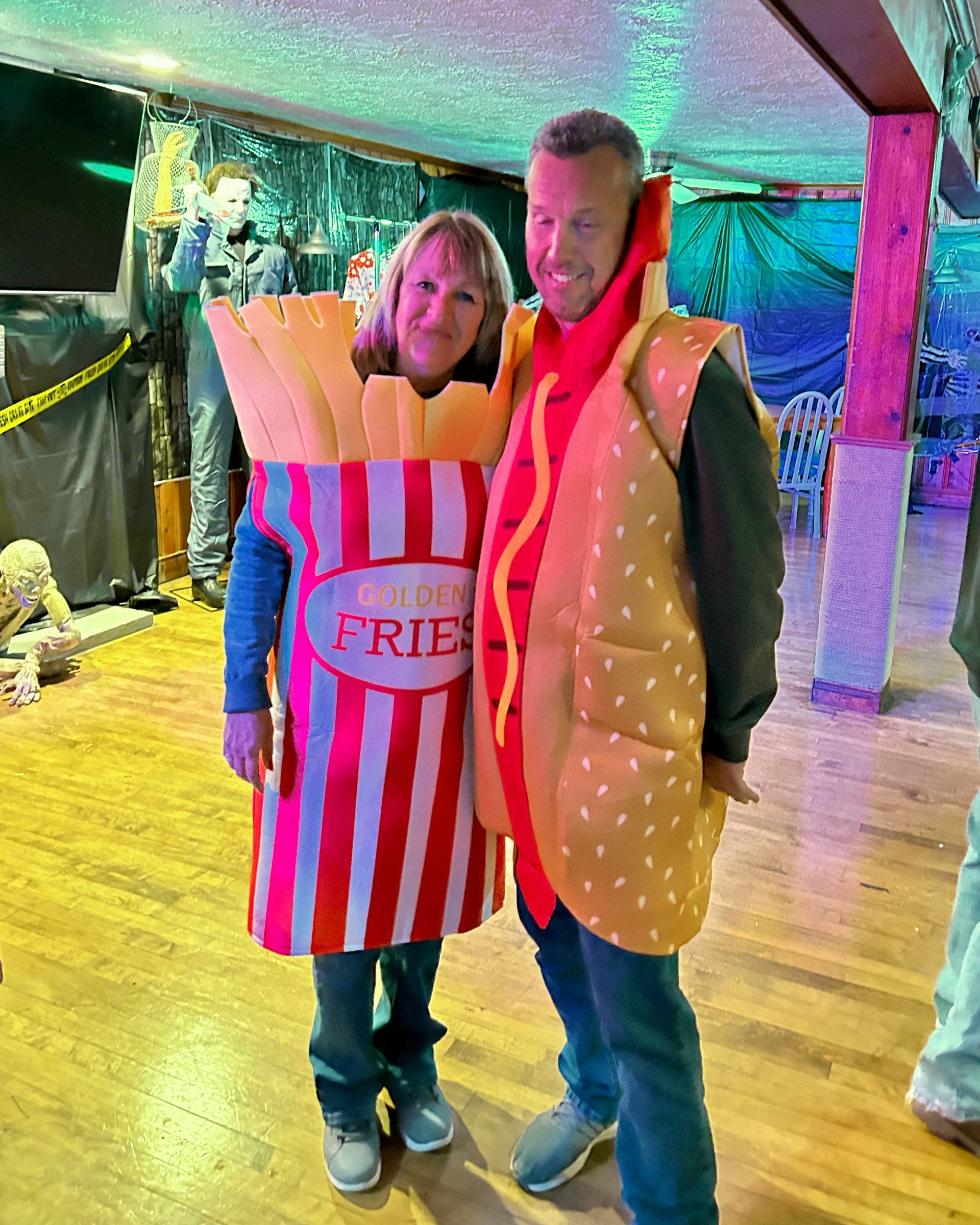 A man and a woman are dressed up as french fries and hot dogs.