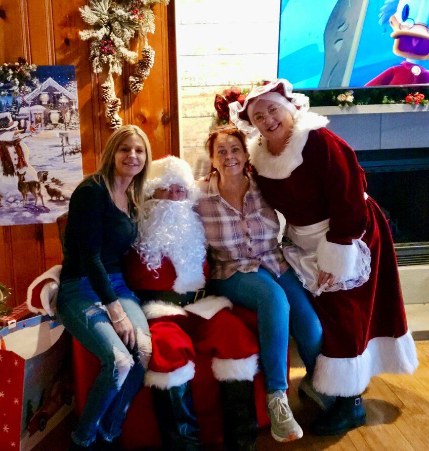 Three women are posing for a picture with santa claus