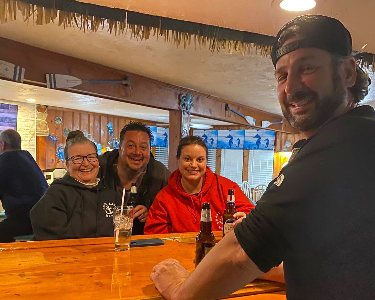 A group of people are sitting at a bar drinking beer.
