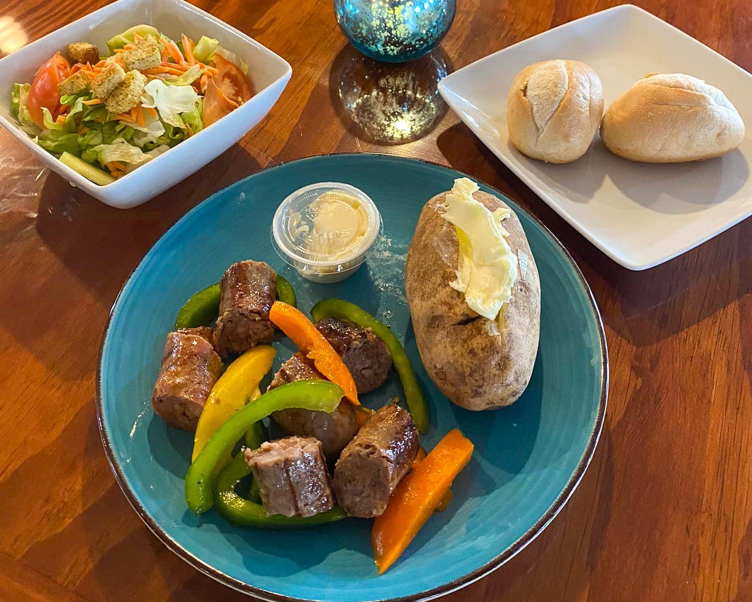 A plate of food with a baked potato and a salad on a table