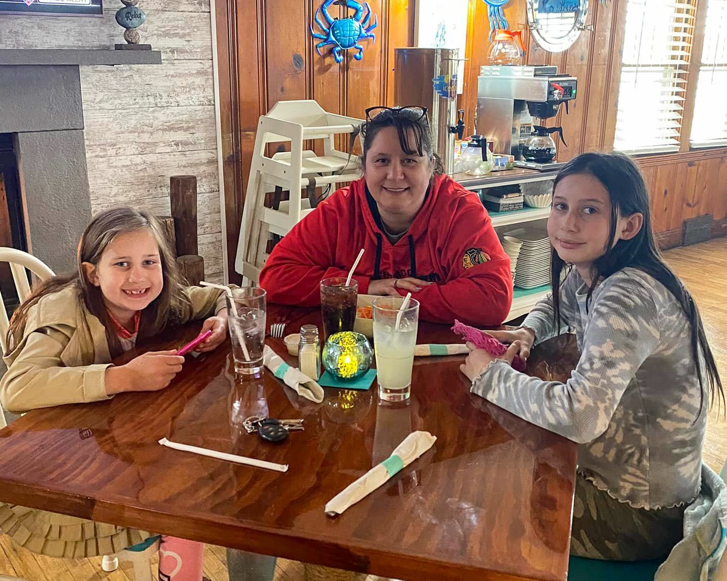 A woman and two girls are sitting at a table in a restaurant.