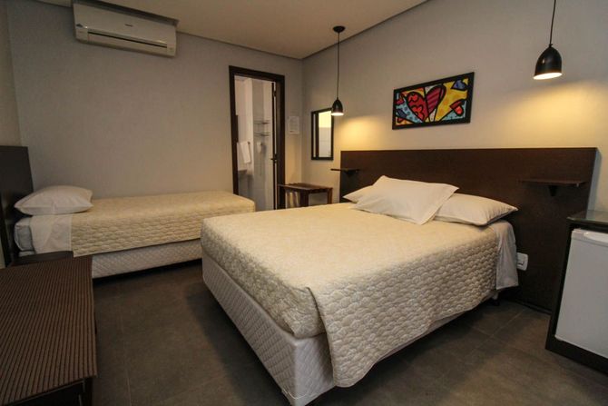 Um quarto de hotel com cama king size e duas camas de solteiro