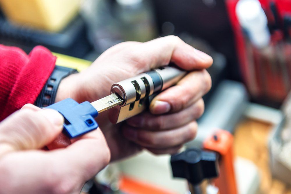 A Close Up Of A Person Holding A Key And A Lock Cylinder — Grafton Locksmith Service In Maclean, NSW