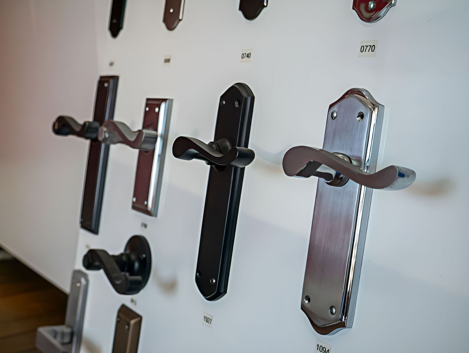 A Variety Of Door Handles Are Displayed On A Wall — Grafton Locksmith Service In Woolgoolga, NSW