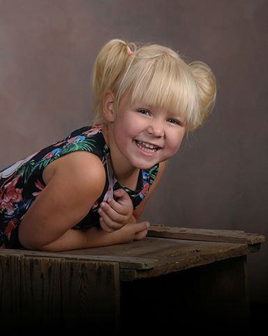 photo of a kid smiling leaning on a table