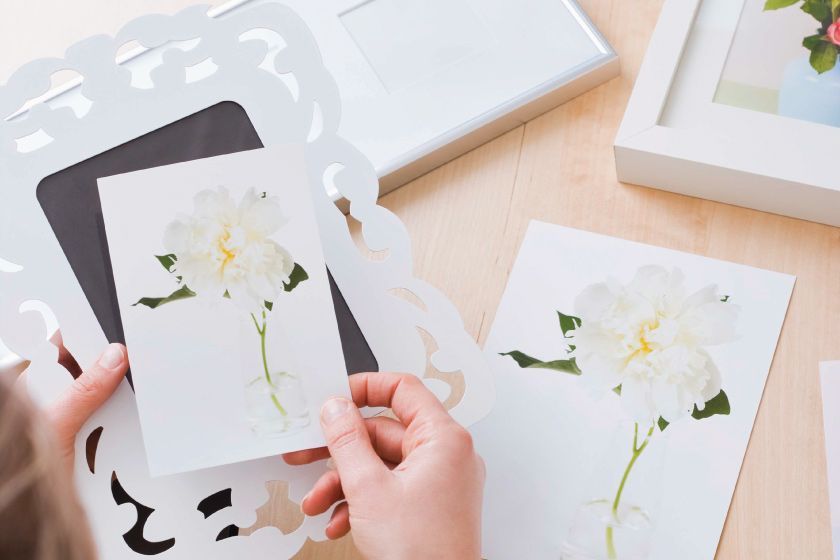 A person holding a frame and a picture with flowers on it