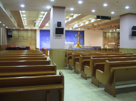 Small church interior with polished pews, altar cross, and soft ceiling lights.