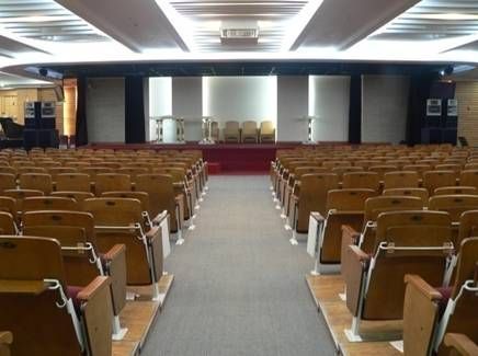 Simple auditorium with wooden seats and a clean, stage-centered layout.