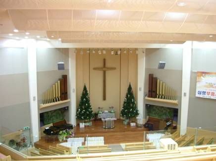 Bright church altar with cross, pipe organs, and Christmas tree decorations