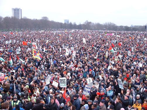 Massive outdoor protest crowd holding signs and banners