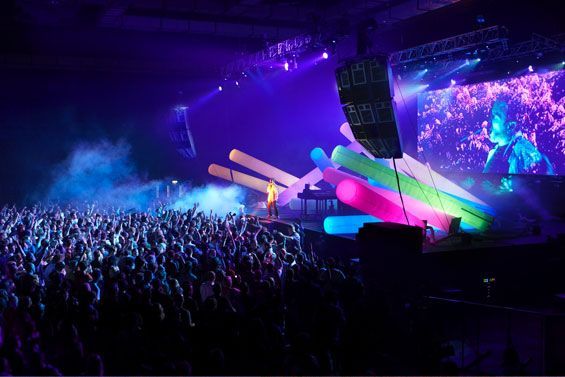 Singer performing a live concert with neon stage lights.