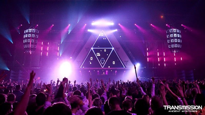 Indoor EDM show with a triangular LED stage and a packed crowd
