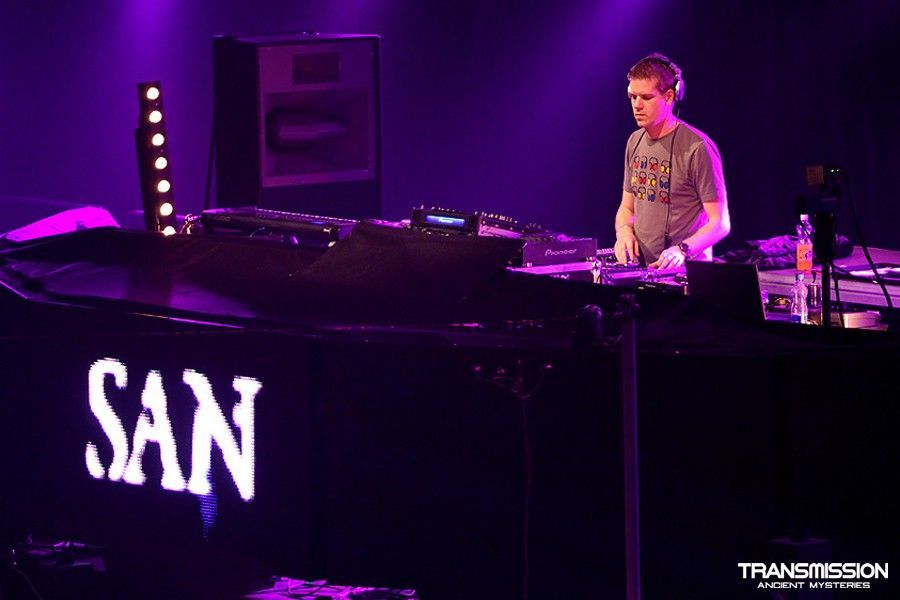 DJ SAN mixing live set with stage lighting effects.