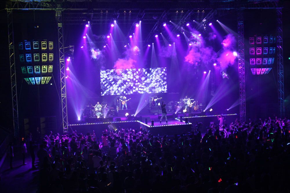Live concert with LED screen, purple lights, speakers.