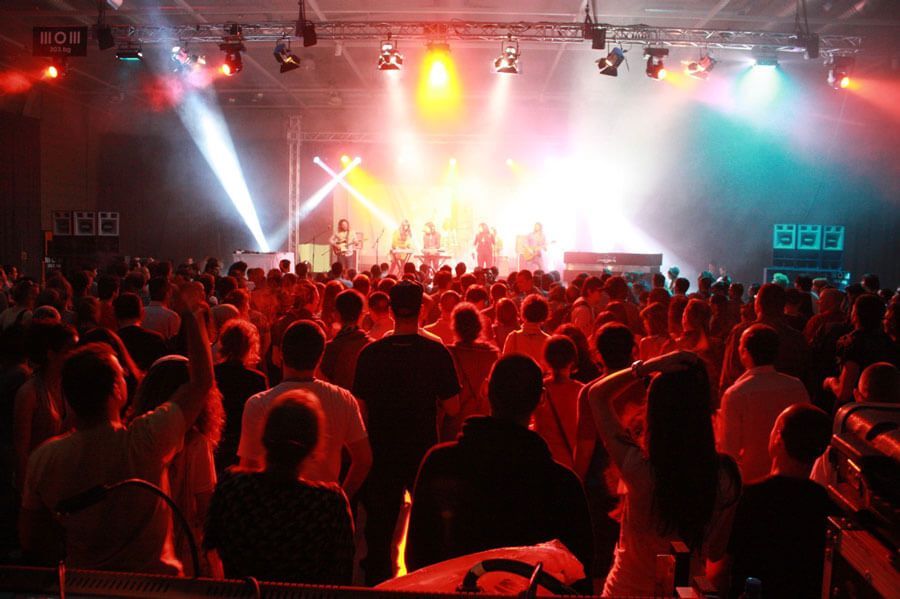 Music fans enjoying live band under concert lights.