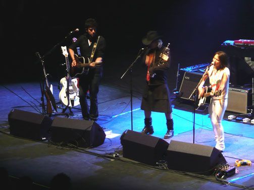 Live band playing guitars on a dark concert stage.