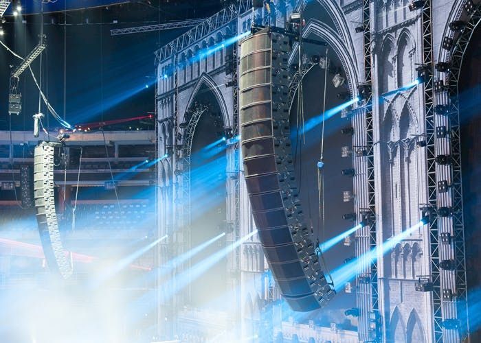 Concert venue with curved line array speakers and gothic-style stage design.