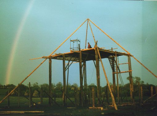 Wooden stage construction with scaffolding under rainbow sky