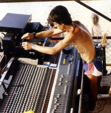 Sound engineer operating a large mixing console at an outdoor concert