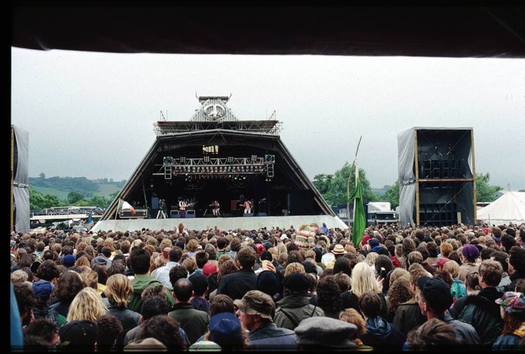 Outdoor music festival stage with large crowd and sound towers